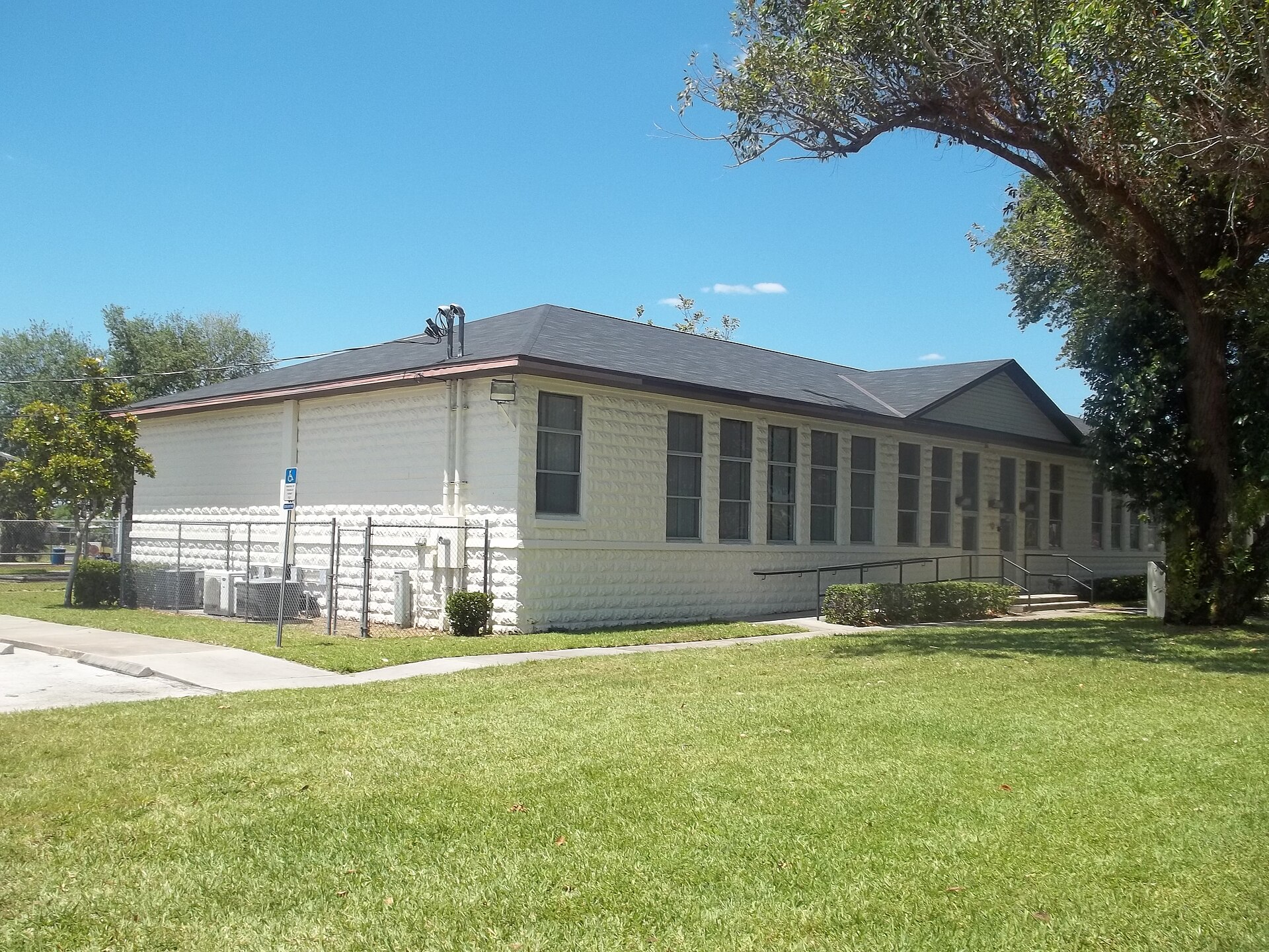 The side of Cocoa Junior High School, showing its hipped roof and rows of tall windows in rusticated block walls.